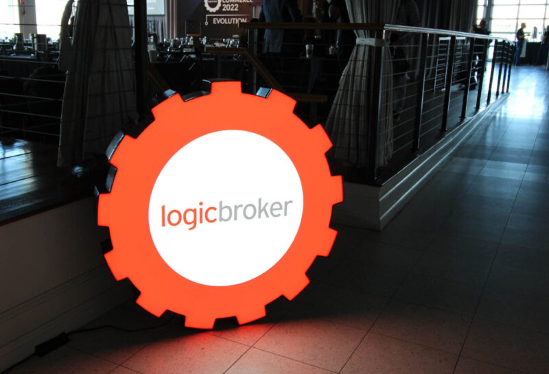 Large Logicbroker gear logo sign on the floor at Connected Commerce 2023
